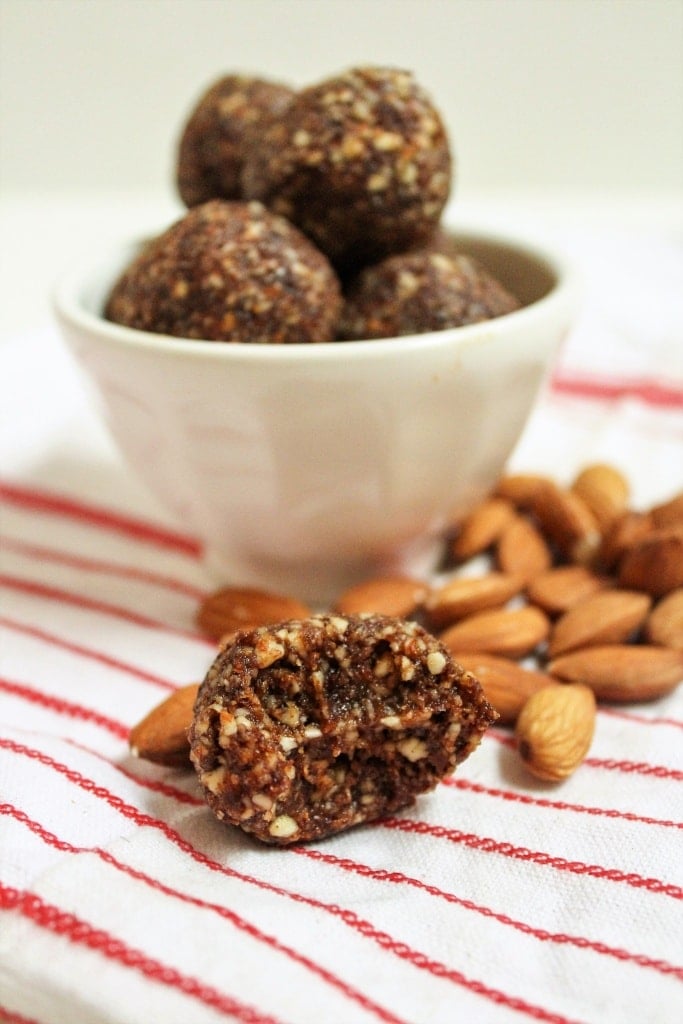 raw almonds and energy bites in a white bowl