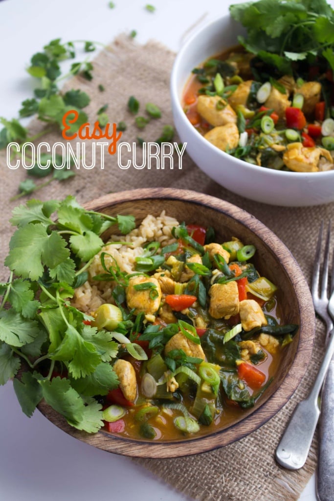 chicken curry with coconut milk in a wooden bowl with herbs and veggies