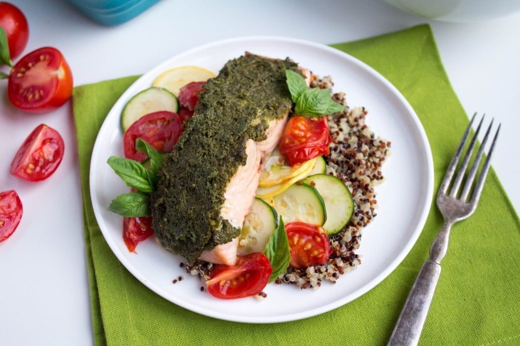 pesto baked salmon with zucchini, summer squash, tomatoes, and quinoa on a plate