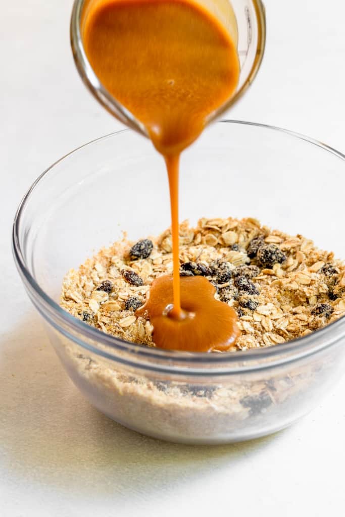 pouring peanut butter mixture into dry cookie dough ingredients
