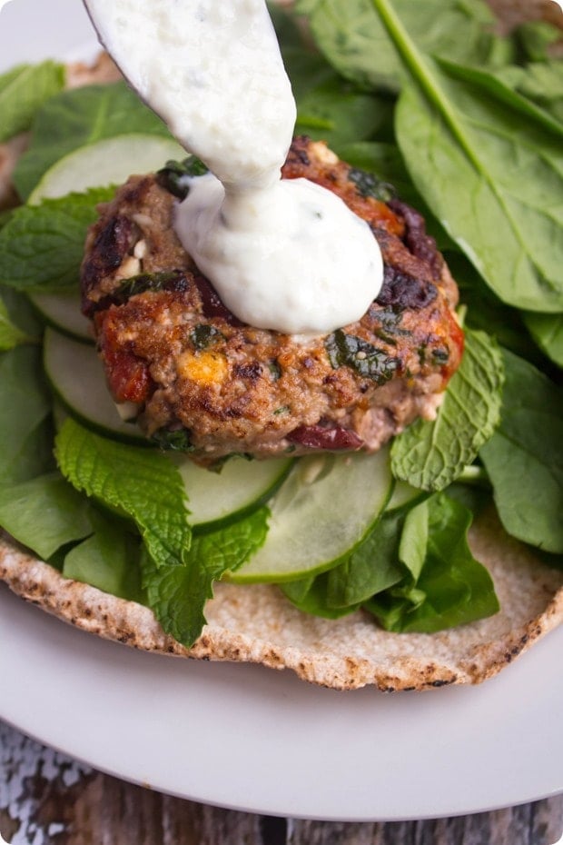 greek lamb burgers with feta drizzled with yogurt sauce in a pita