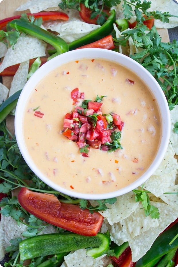 spicy queso dip with diced tomatoes on top, served with bell peppers