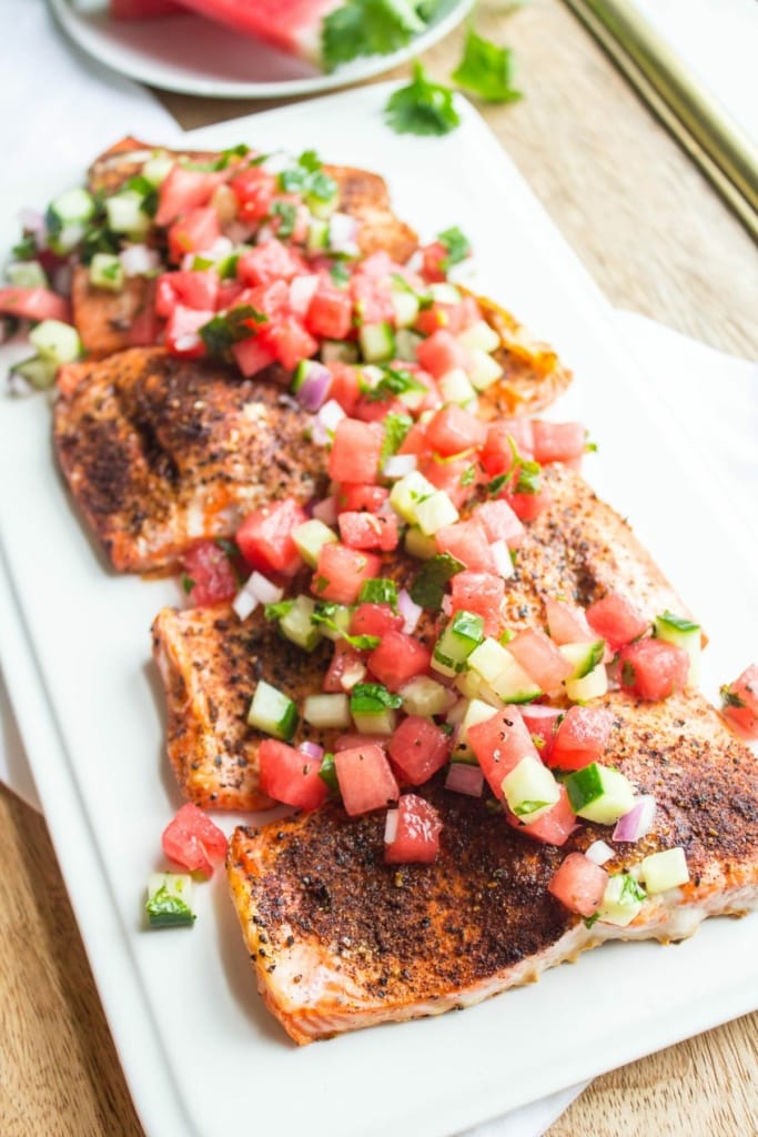 roasted salmon filets on a long white platter with watermelon cucumber salsa on top