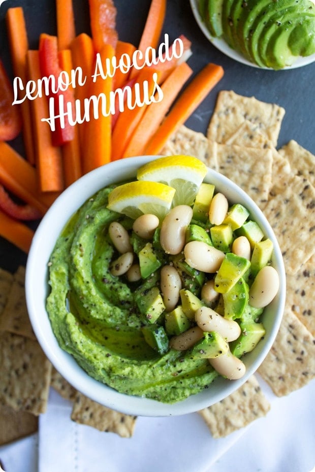 lemon avocado white bean hummus in a small white bowl with carrots and crackers 