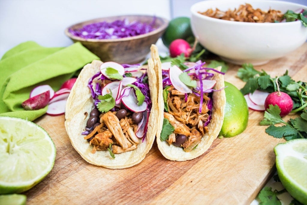 meatless jackfruit carnitas tacos on a wooden platter with limes