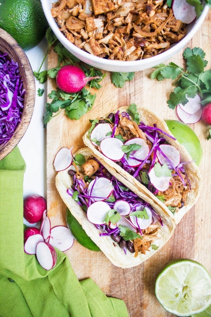 jackfruit tacos on a wooden platter with purple cabbage and radishes