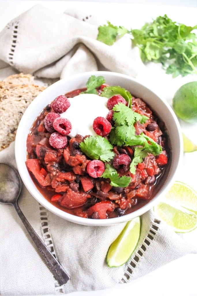 vegan black bean chili with raspberries in a bowl topped with a dollop of Greek yogurt