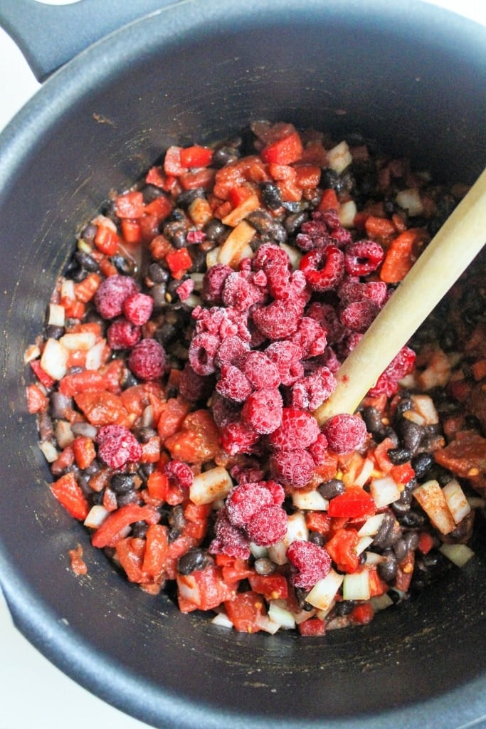 black bean chili in a pot with frozen raspberries