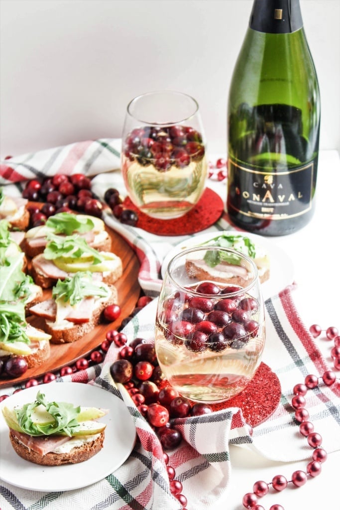 Ham and Pear Goat Cheese Crostini next to Cava sparkling wine with cranberries