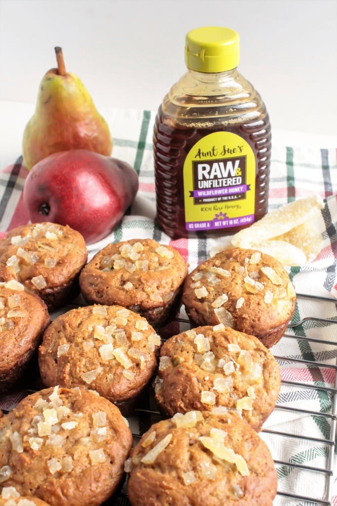 pear muffins on a cooling wire rack with pears and bottle of honey in the background