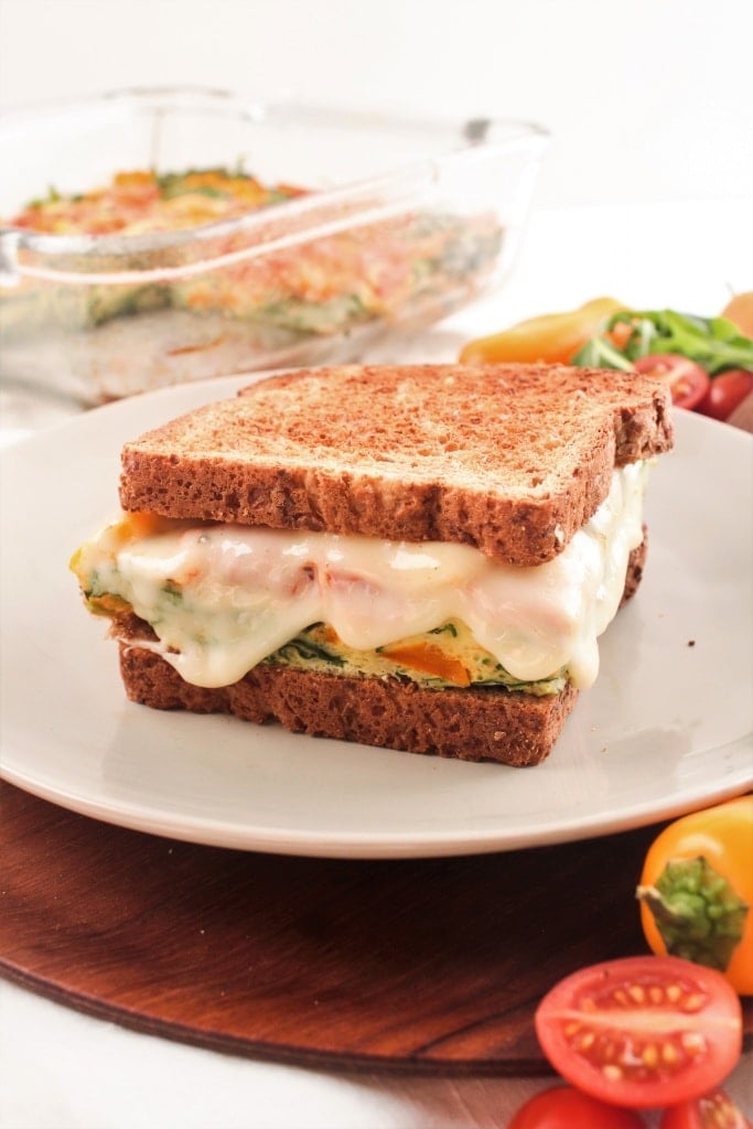 cheesy and veggie-packed breakfast sandwich on a plate