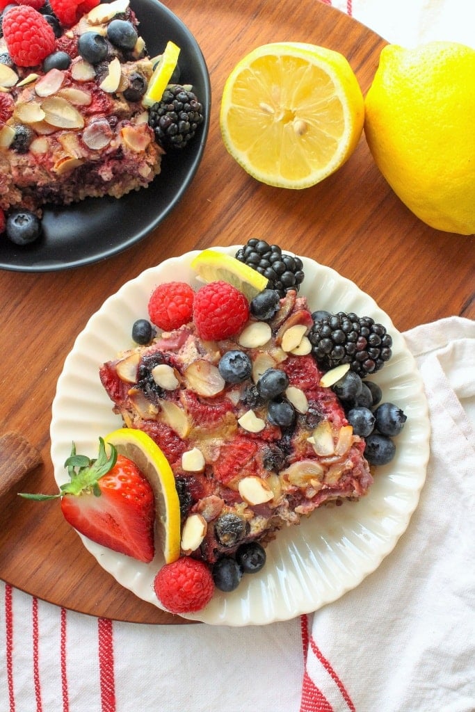 quinoa breakfast bake on a white plate with sliced berries and lemons