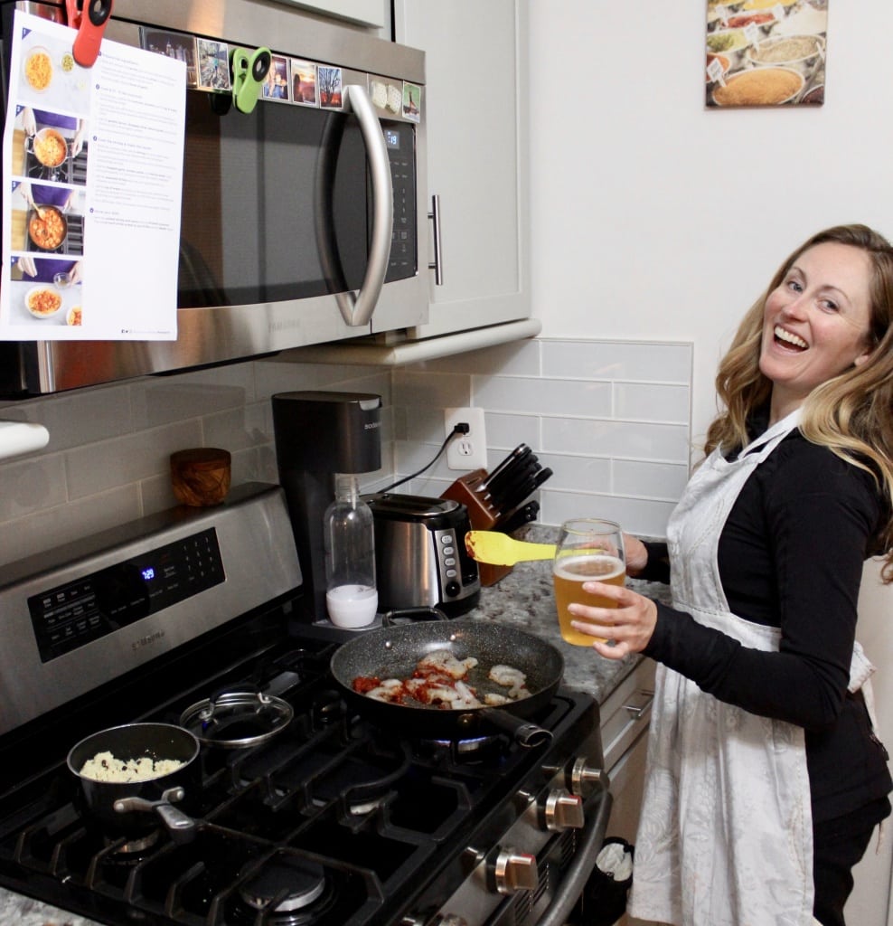 standing at the stove cooking some blue apron shrimp