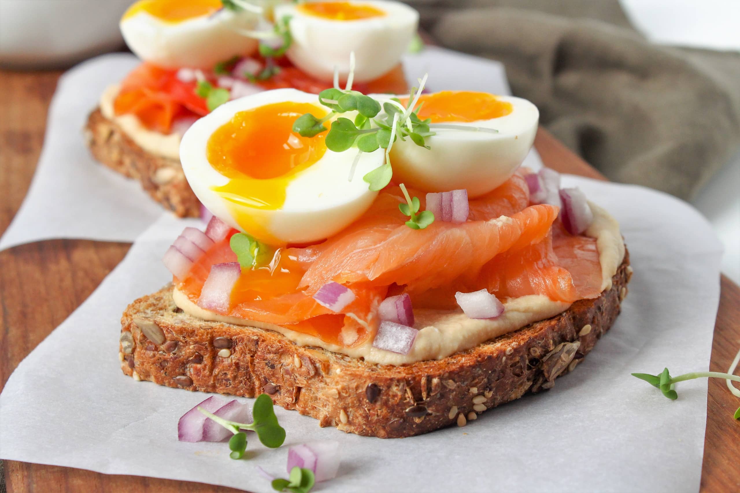 smoked salmon hummus toast with soft boiled eggs and herbs