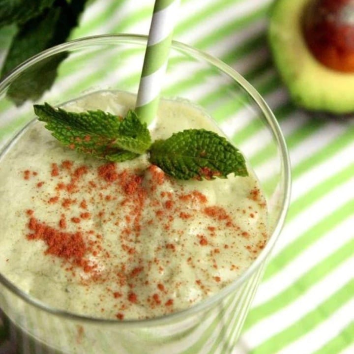 healthy shamrock shake in a glass with mint and avocado and a green striped straw