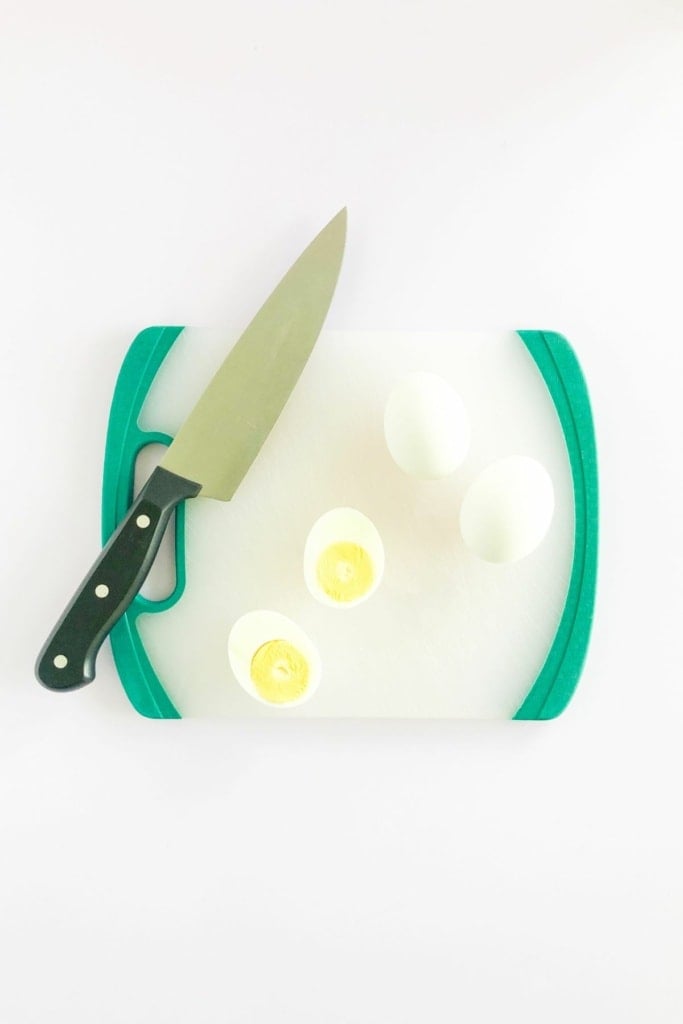 cutting board with hard-boiled egg sliced open and a large knife beside it