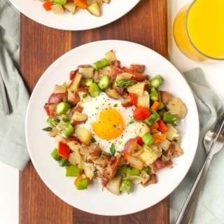 potato breakfast hash with sheet pan baked eggs on a plate next to a glass of orange juice
