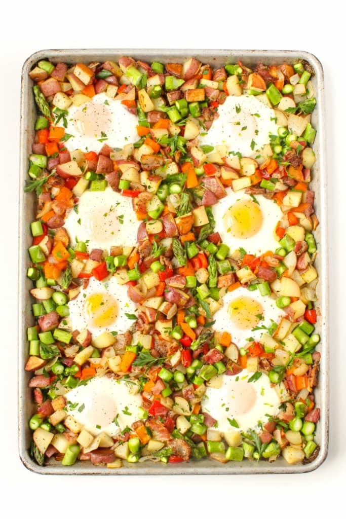 baked eggs on a sheet pan with roasted vegetables, potatoes, and bacon
