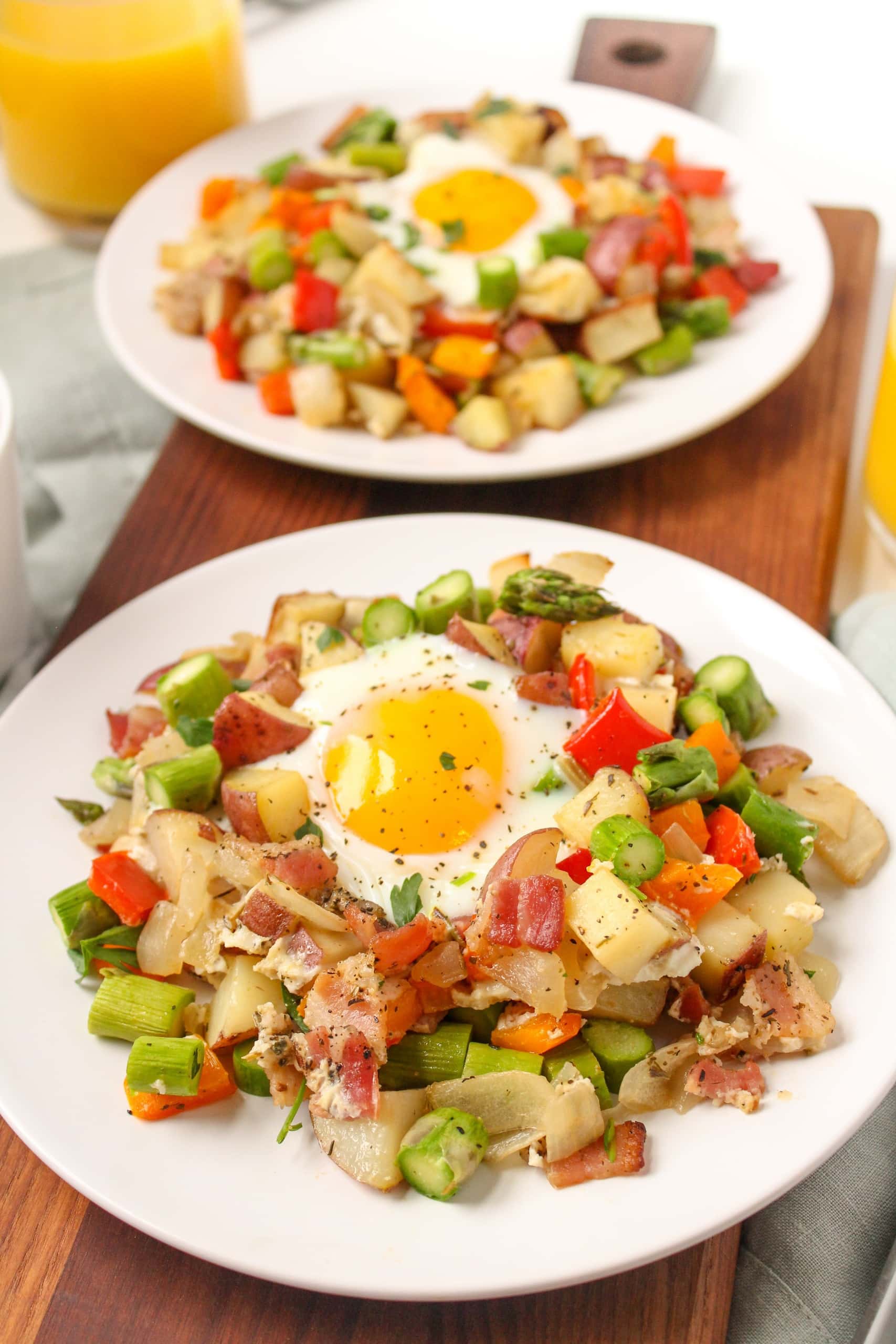 sheet pan eggs with potato breakfast hash on two plates sitting on a wooden platter