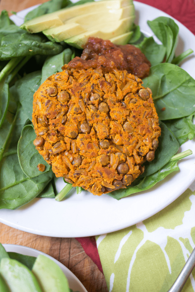 veggie burger patties on a plate with spinach and avocado