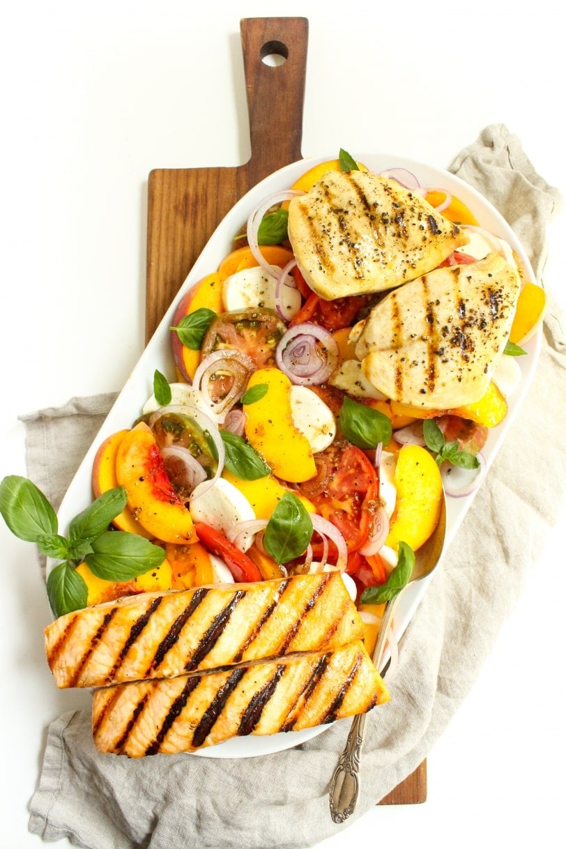 heirloom tomato peach caprese salad served on a long plate with towel underneath it