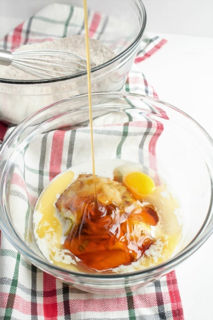 almond milk, melted butter, egg, honey, and more baking ingredients in a large glass bowl