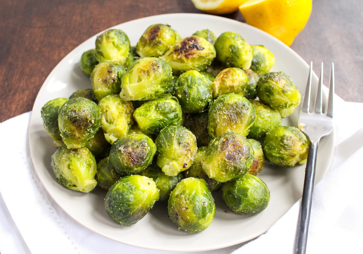 roasted brussels sprouts on a white plate with lemons