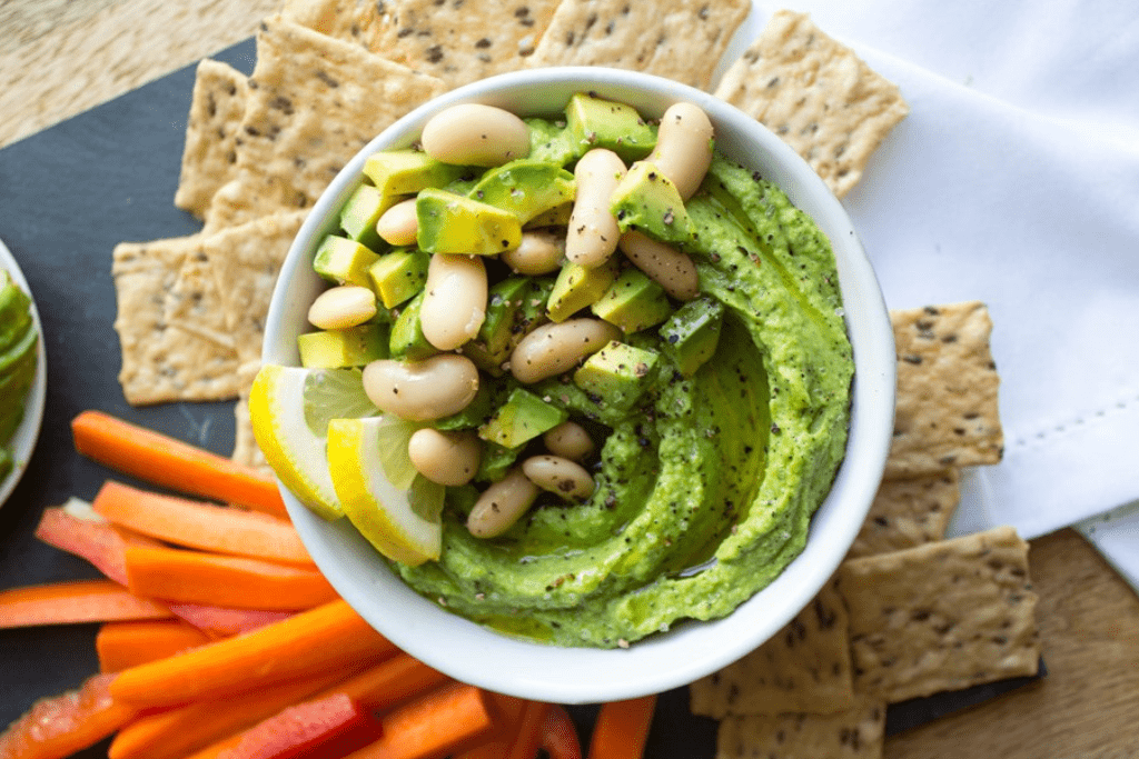 vegan lemon avocado hummus dip with crackers and carrot sticks