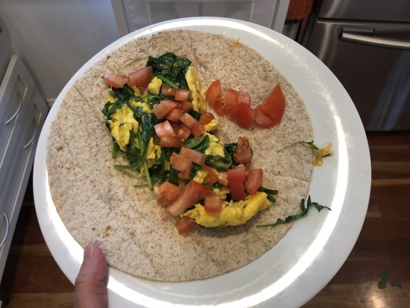 wrap filled with scrambled egg, spinach, tomato, and cheese