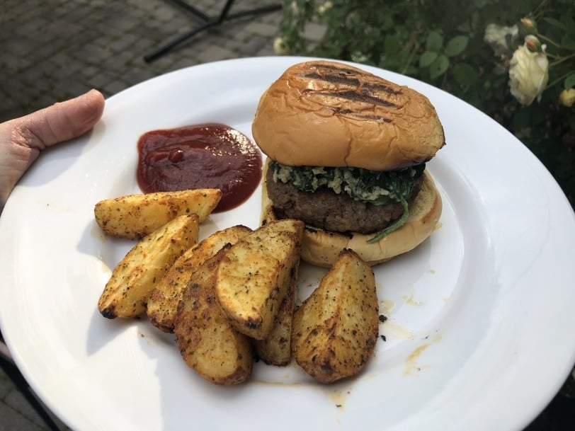 homemade spinach beef burger with roasted potatoes on a white plate
