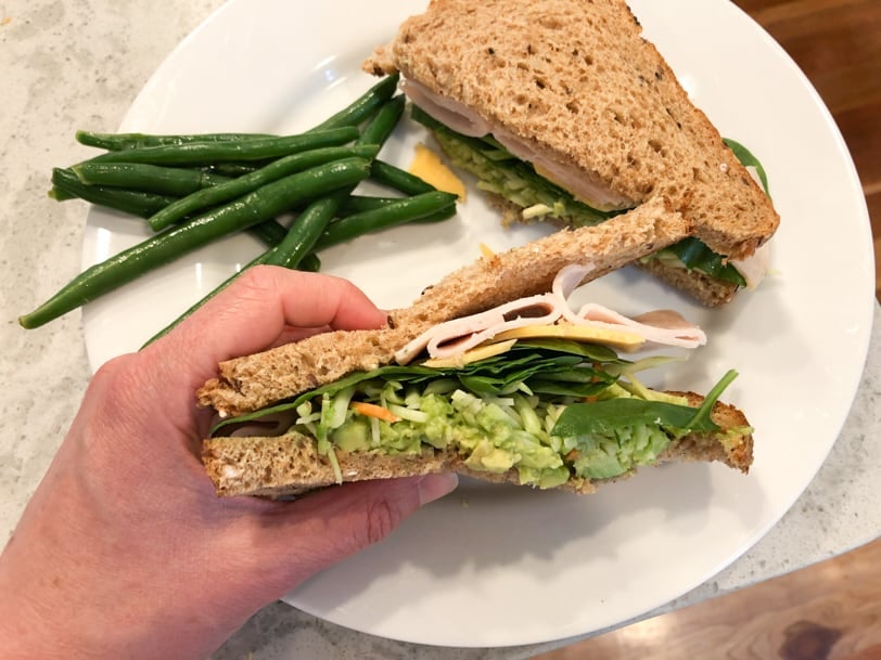 turkey sandwich with guacamole, cheese, and string beans