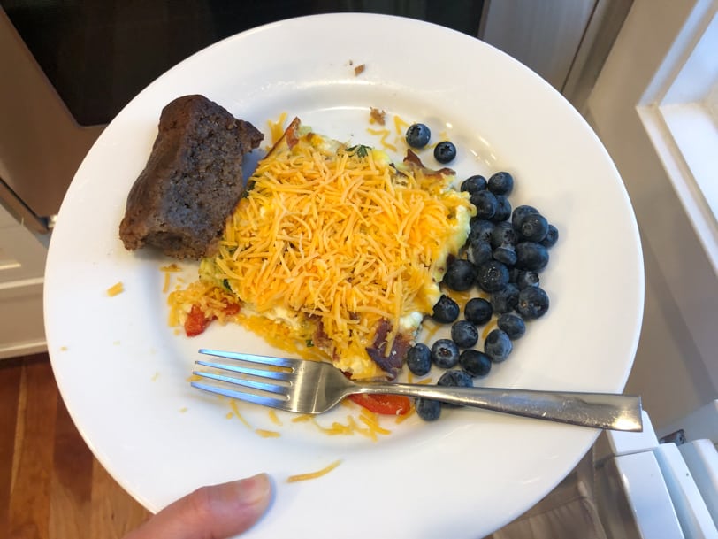 leftover veggie egg casserole with shredded cheese on top, banana bread, and blueberries