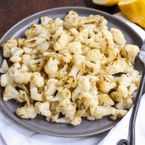 roasted cauliflower on a white plate with lemons