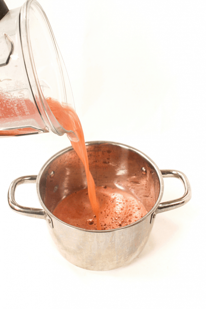 pouring watermelon balsamic glaze into a saucepot