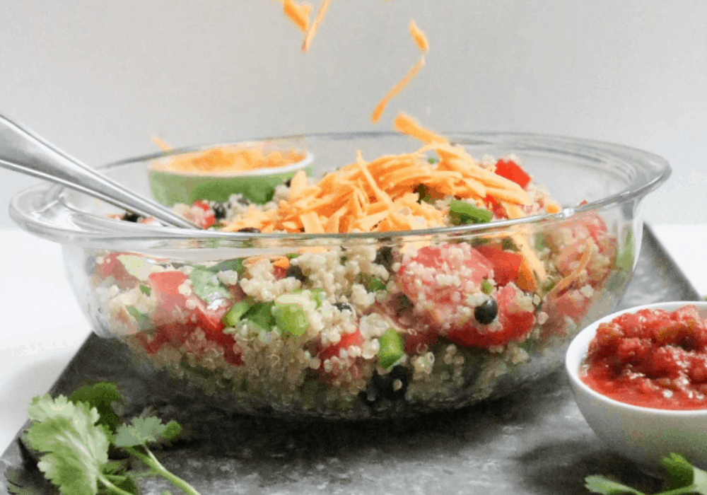 quinoa taco salad in a bowl with shredded cheese and salsa