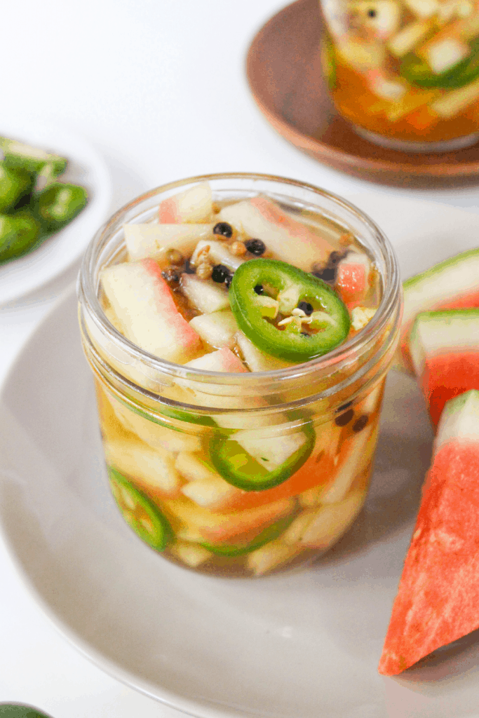 spicy pickled jalapenos and watermelon rinds in a jar