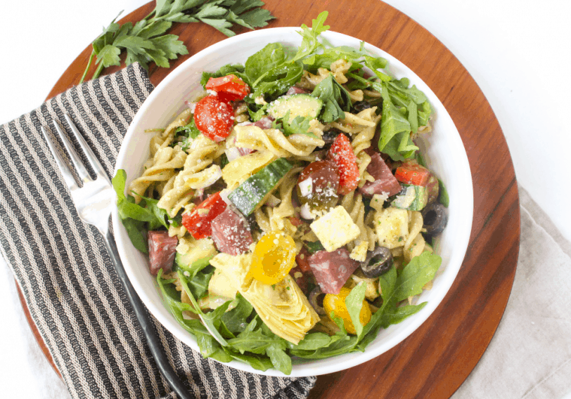 Italian pasta salad on a wooden platter with a striped kitchen towel