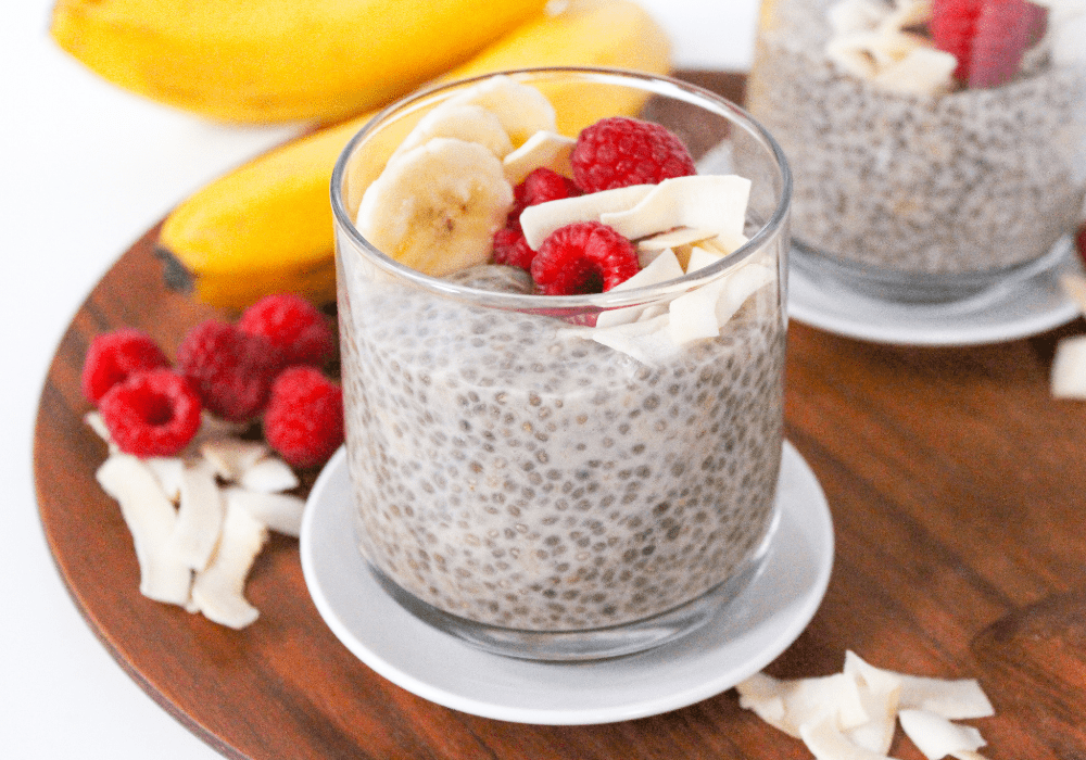 chia pudding in a glass jar with sliced bananas, raspberries, and flaked coconut sprinkled on top