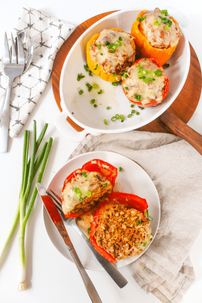 flatlay of stuffed pepper cut in half with white oval baking dish