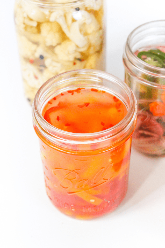 close up of fermenting vegetables in mason jars with brine