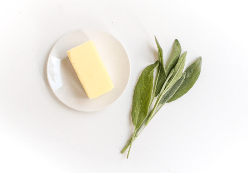 sage butter sauge ingredients: fresh sage leaves and a stick of butter on a white plate