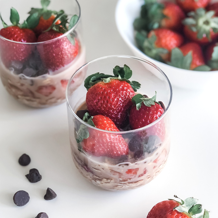 chocolate strawberry overnight oats in jars with a bowl of strawberries in the background
