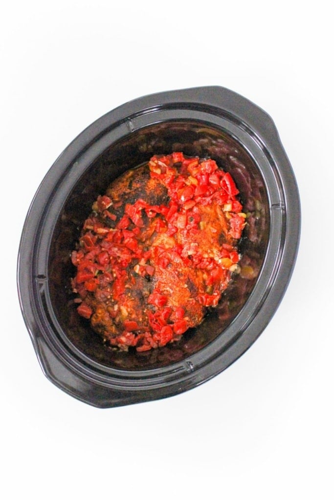 a crockpot insert with chicken breasts and diced tomatoes