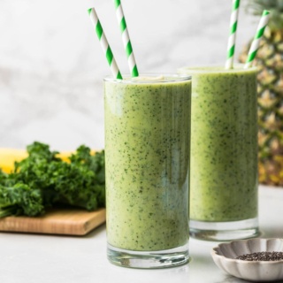 pineapple mango kale smoothie with Greek yogurt in two tall glasses with green striped straws