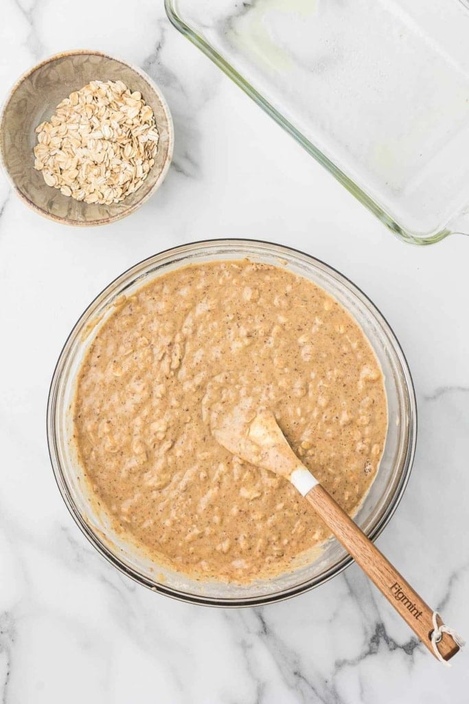 peanut butter banana bread batter with oats in a glass bowl with a spatula