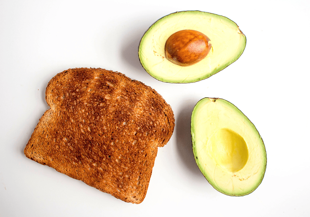 a piece of toast and an avocado sliced in half