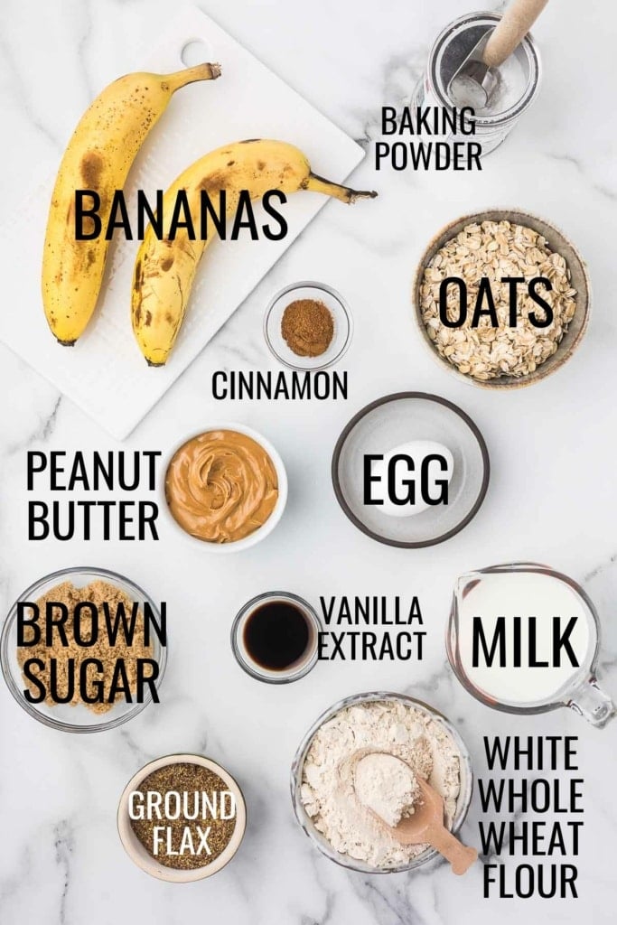 white whole wheat flour, oats, brown sugar, peanut butter, bananas, and more baking ingredients on a marble countertop