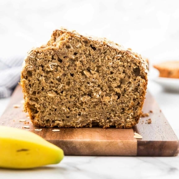 slice loaf of whole wheat peanut butter banana bread on a wooden cutting board
