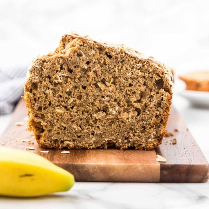 slice loaf of whole wheat peanut butter banana bread on a wooden cutting board