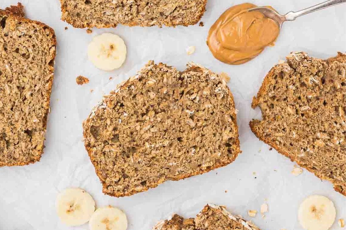 slice of whole wheat banana bread with a spoon of peanut butter next to it